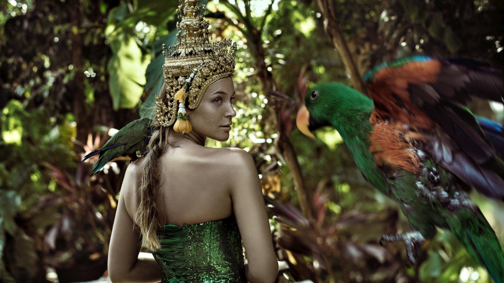 Asian queen holding a green parrot