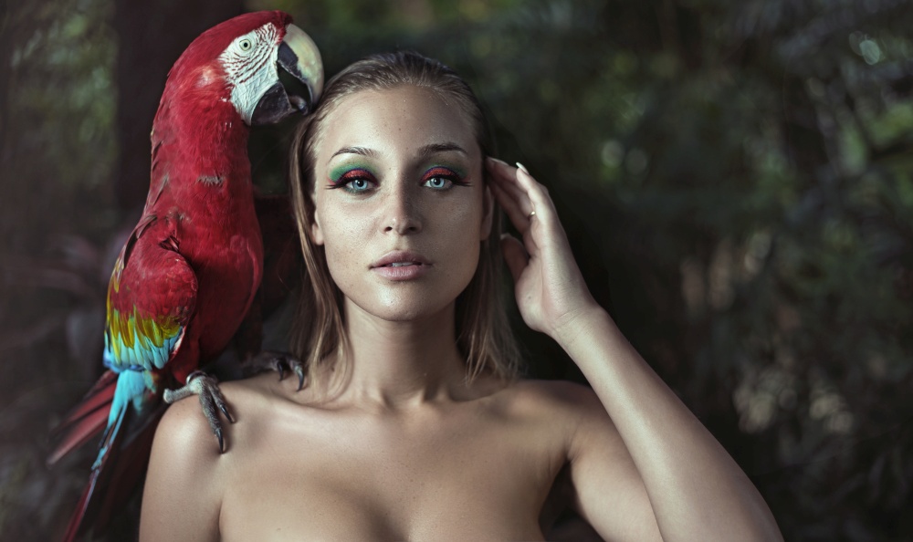 Sensual woman with a colorful ara parrot