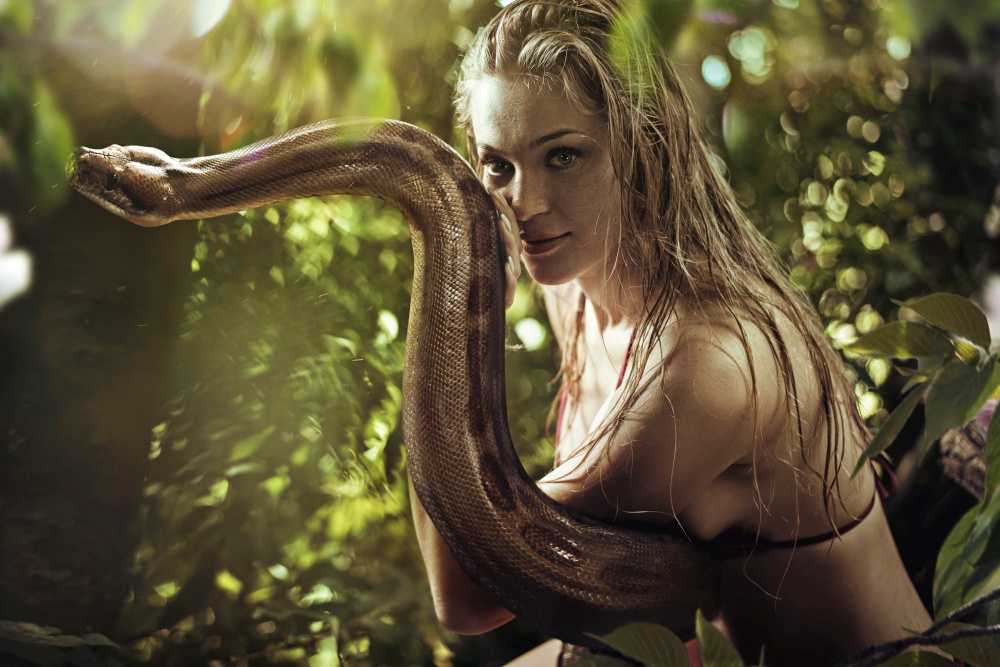Portrait of a pretty blond lady holding a wild snake