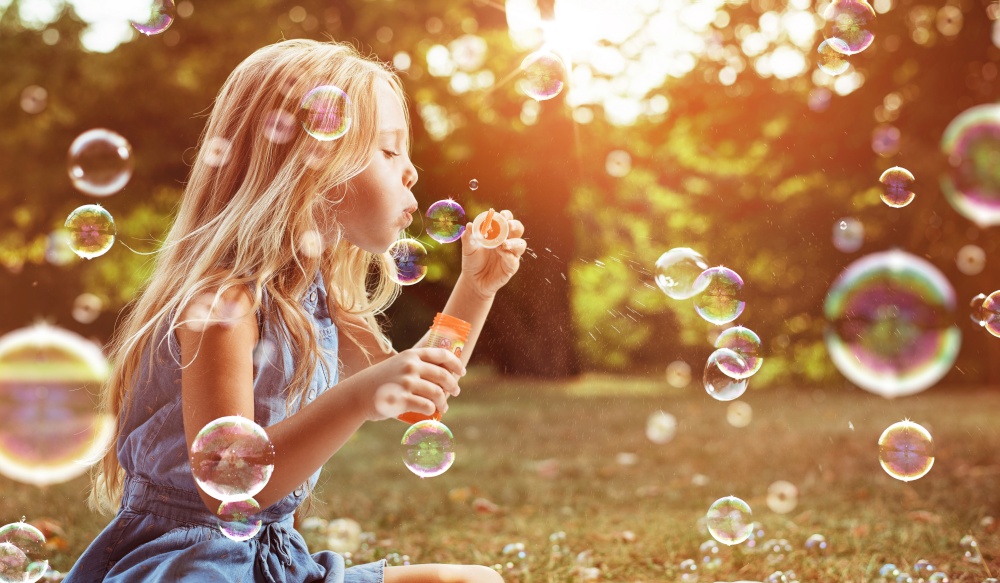 Portrait of a cheerful child blowing soap bubbles