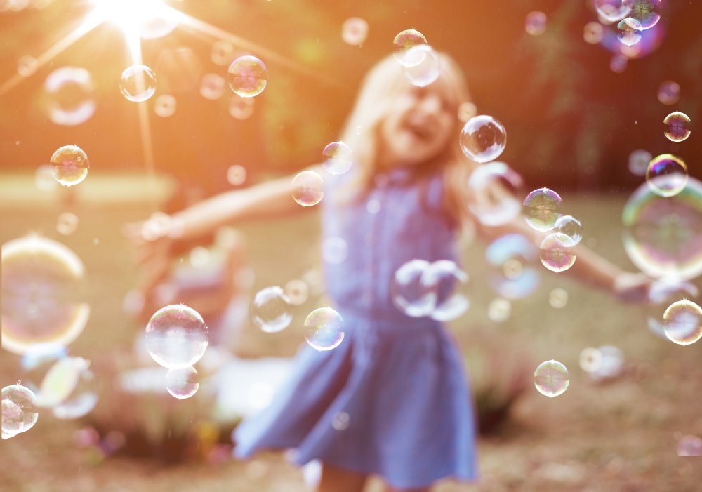 Cheerful, little girl enjoying bubble blowing