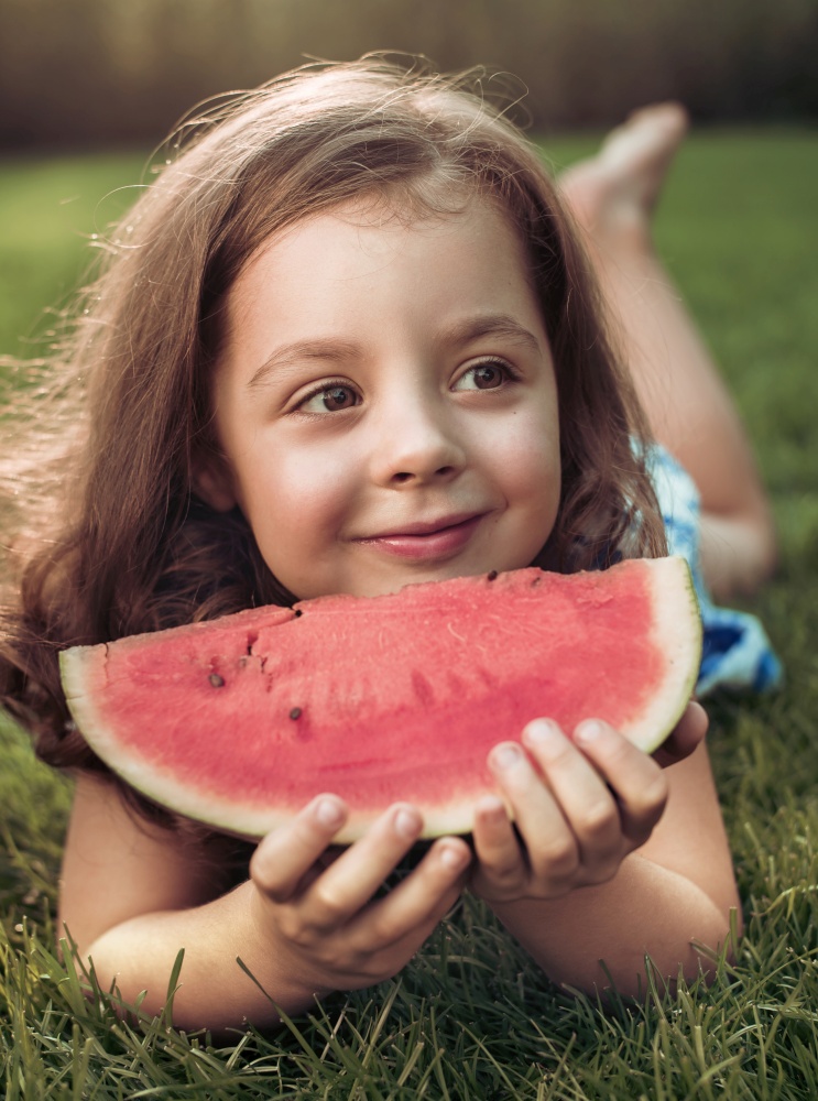 Closeup portrait of smiling child holding watermelon slice in the garden