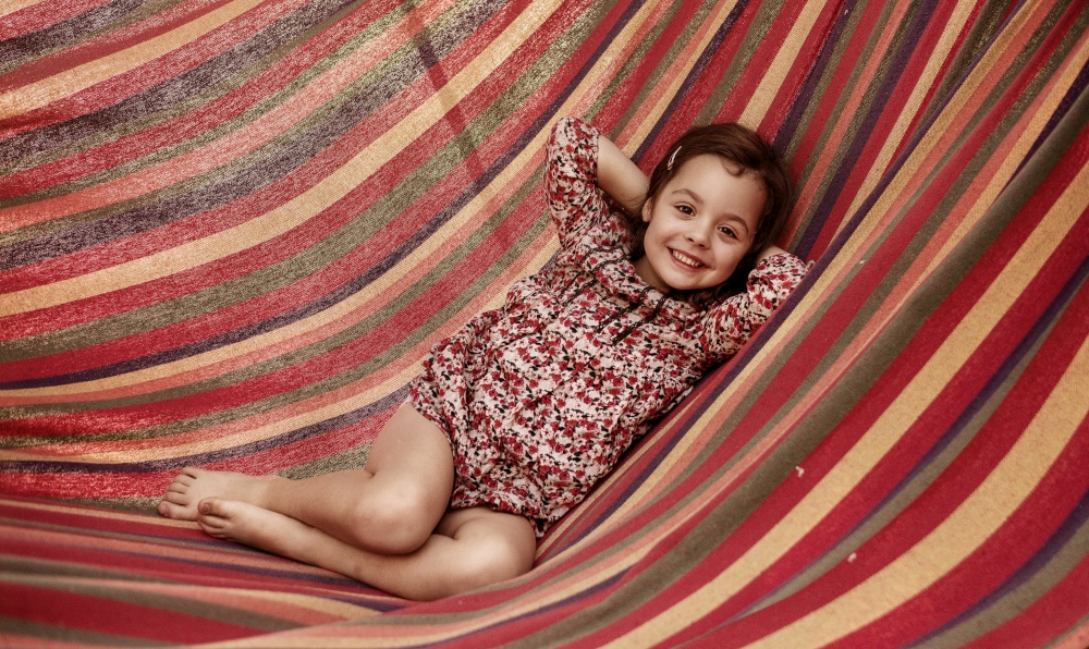 Cute little girl realxing on a colorful hammock