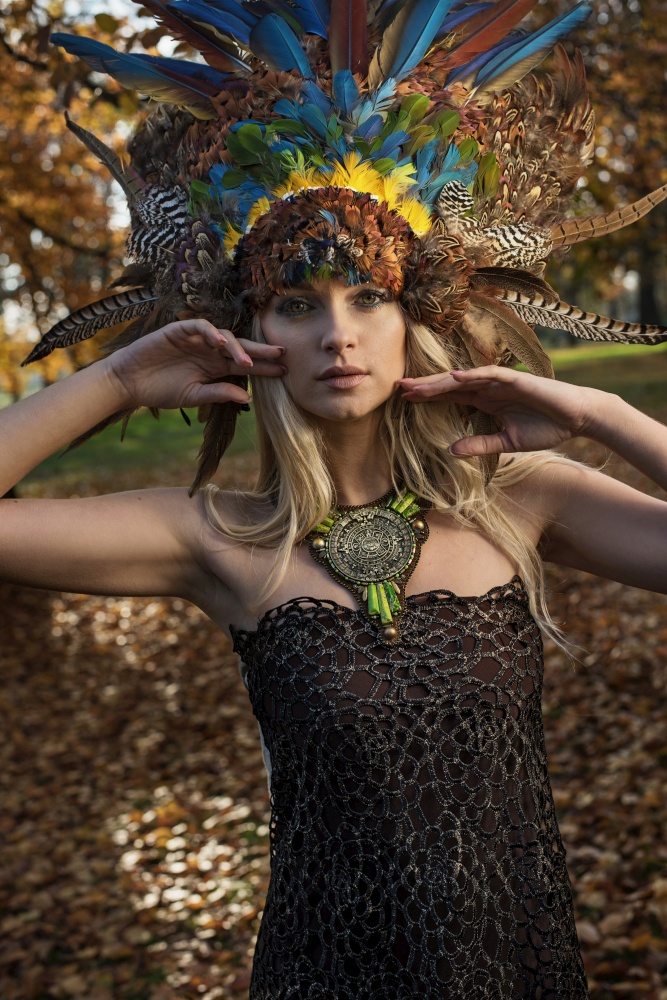 Pretty blond woman wearing coronet made of peacock&rsquo;s feathers