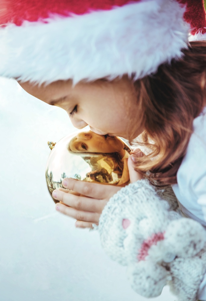Cute, little girl kissing a golden, christmas glass ball