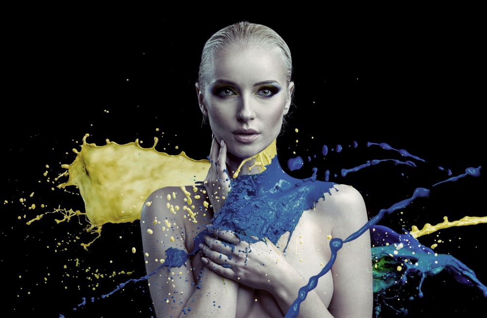 Portrait of colorful paint splashing against a young woman