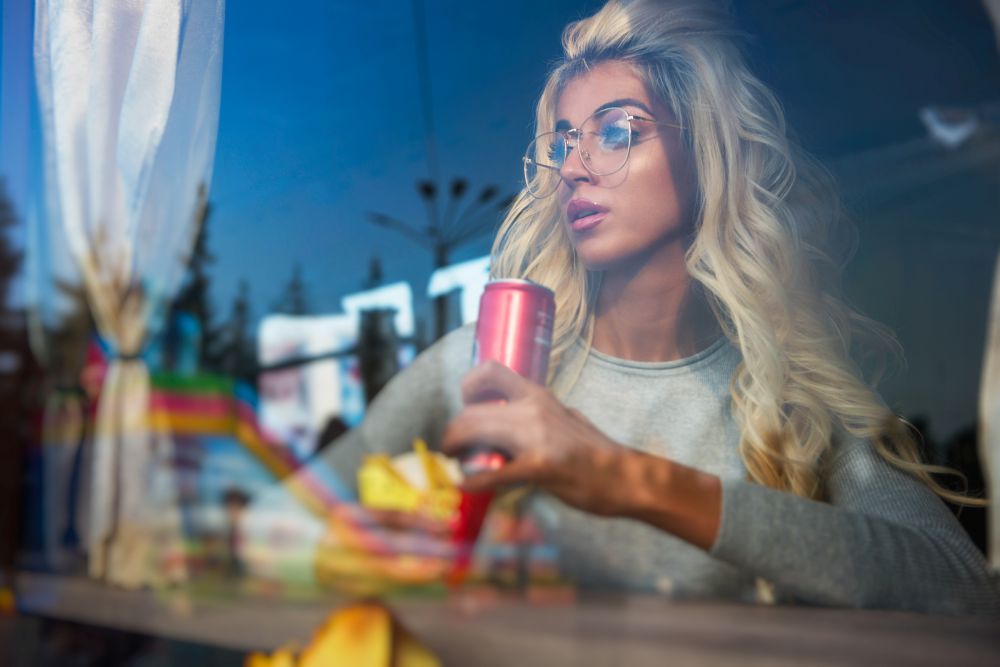 Fast food and leisure concept - beauty young blonde woman eating a fried potato and soda water. Fast food and leisure concept