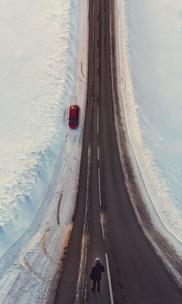 Surreal image with an unusual perspective with a woman on a winter road and car, simultaneous top view and normal view. Surreal image with an unusual perspective with a woman on a winter road and car
