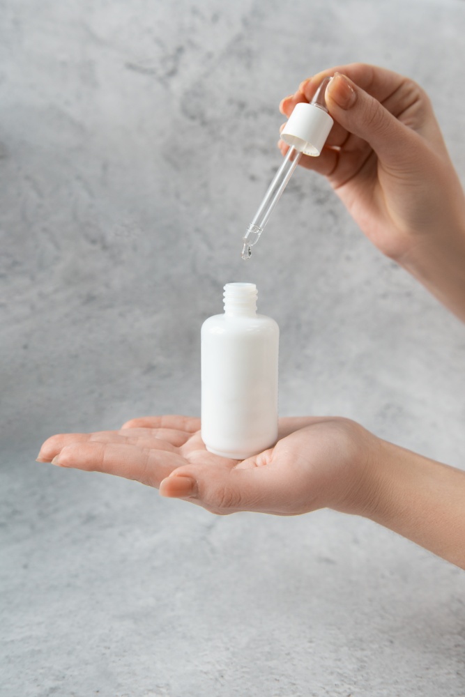 Woman hand with dropper bottle with white transparent liquid. Woman hand with dropper bottle