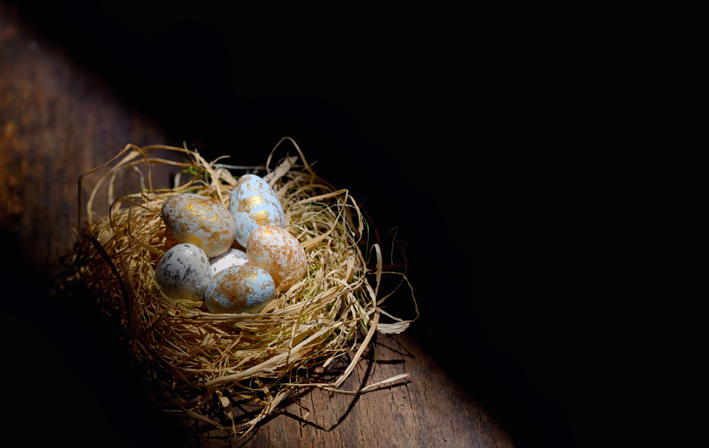 Decorative easter eggs in nest on wooden table