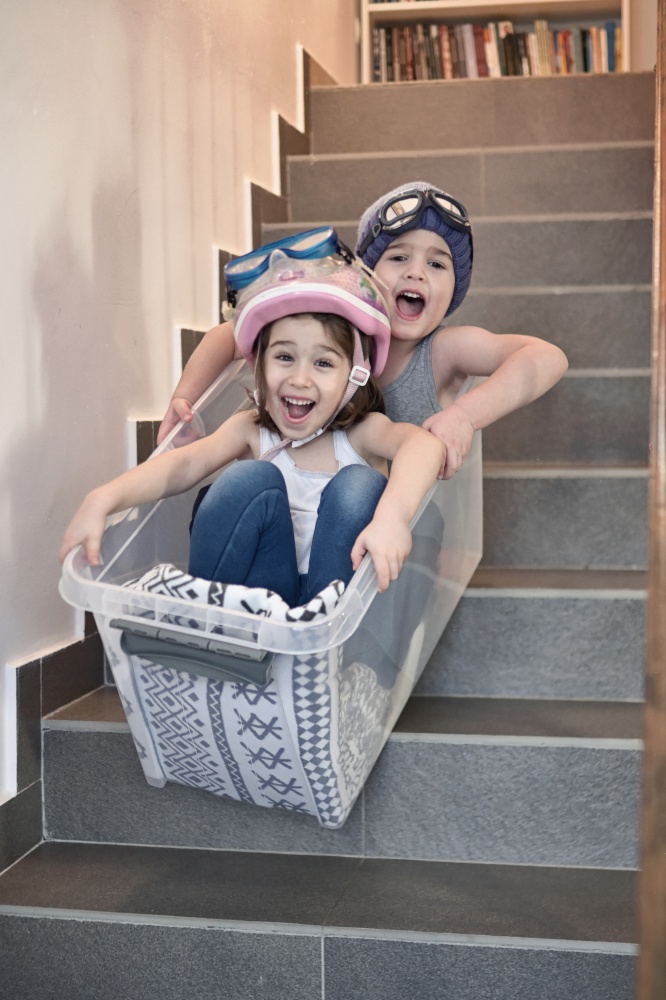 Kids having fun sledding down stairs in a storage box