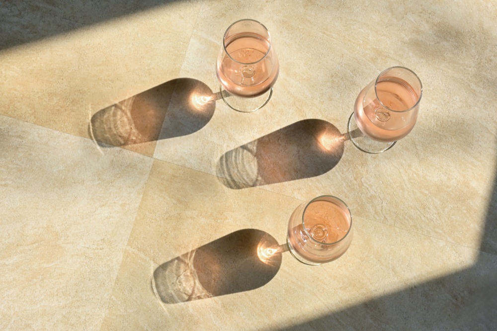Three Glasses Of Rose Wine and Shadow on Stone Table