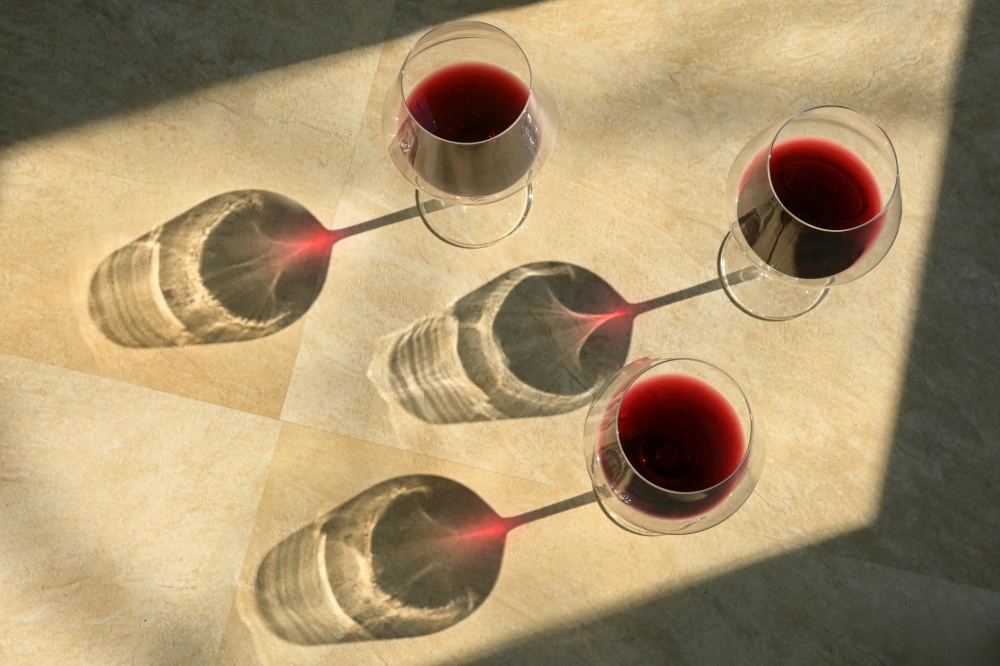 Three Glasses Of Red Wine and Shadow on Stone Table