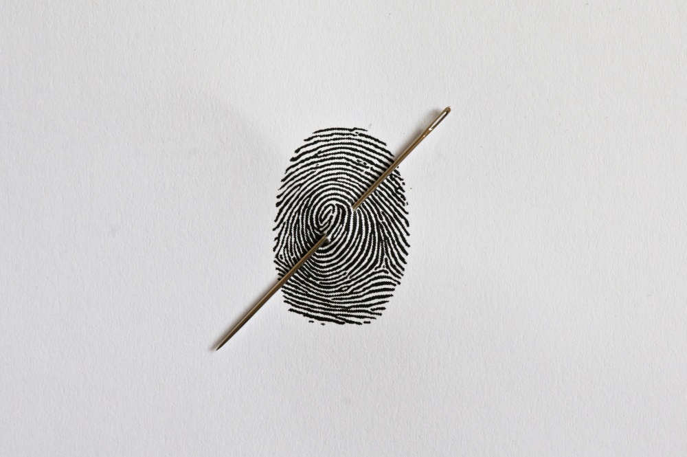 Abstract Thumb Fingerprint and needle through the Paper