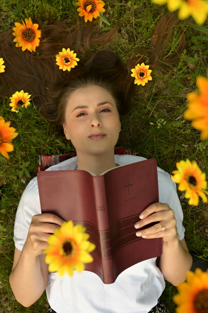 Portrait Of A  Girl With Flowers In Her Hair and Open Bible on Field