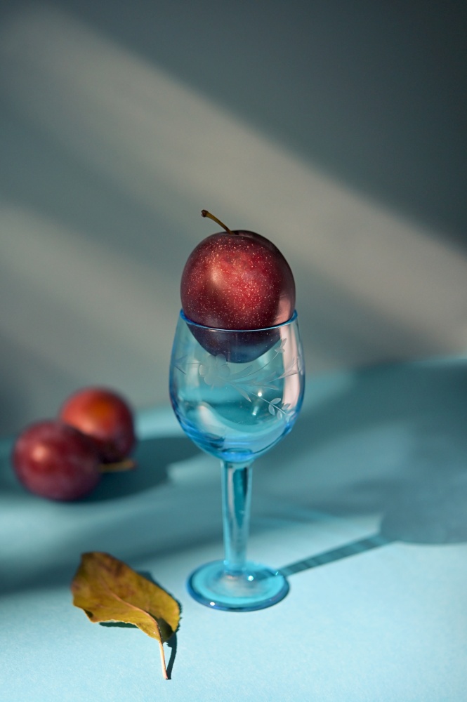 Abstract Ripe plums in small glass shoot in studio