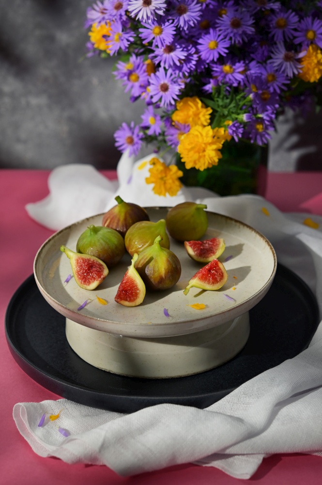 Figs fruits placed on a small plate on a table with a tablecloth and sunshine