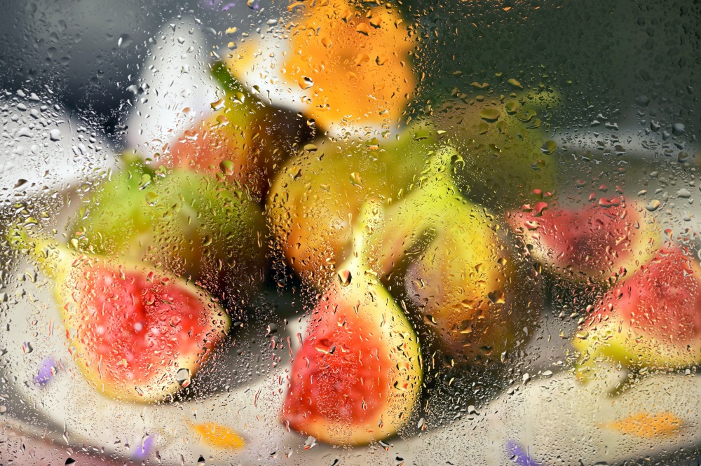 Abstract Figs fruits placed on a small plate behind rainy window