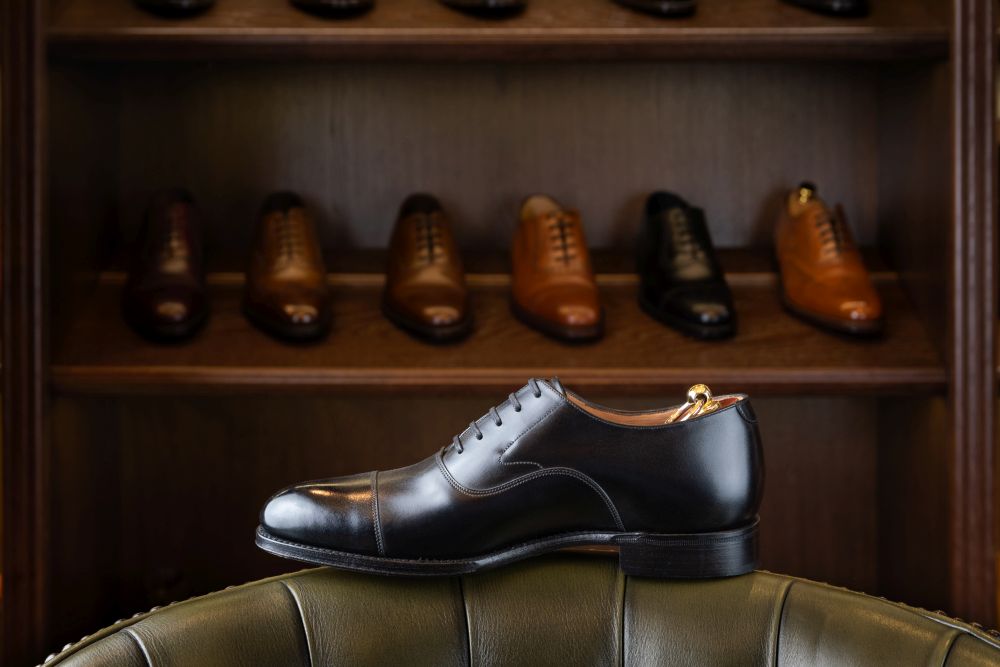 Black full grain leather shoe in front of wooden display in men shoes boutique store.. men footwear boutique store