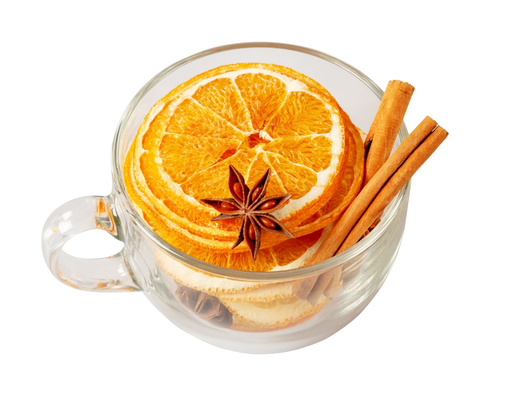 Stack of dried orange slices, cinnamon and star anise in a glass cup. Spices for mulled wine on a white background. Top view
