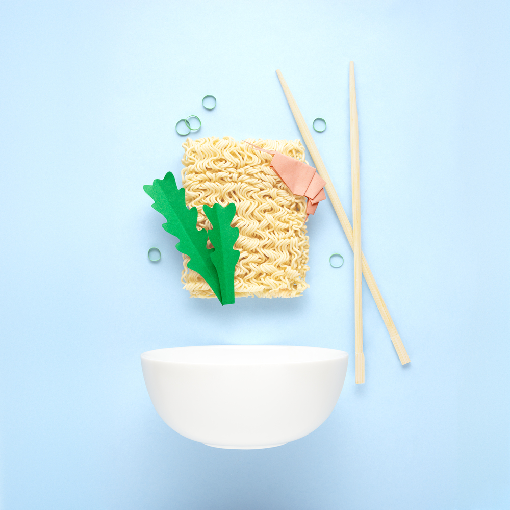 Creative food diet healthy eating concept photo of tasty ramen noodle pasta with shrimps prawns greens chopsticks and bowl on blue background.