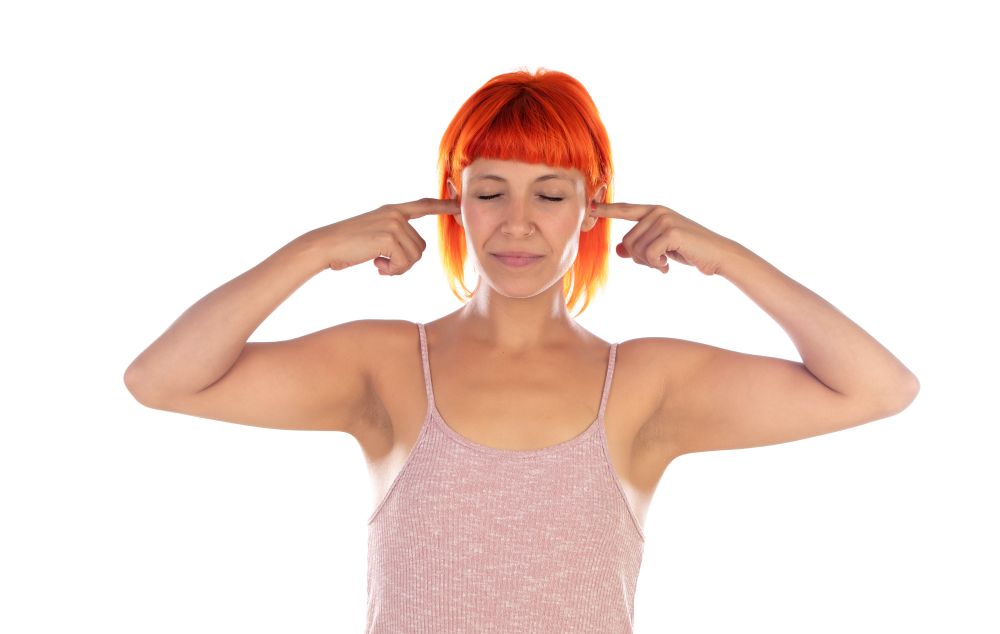Woman with red hair covering her ears with the fingers isolated on a white background