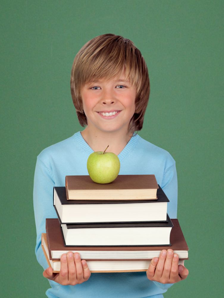 Happy child holding books and a apple with a green background