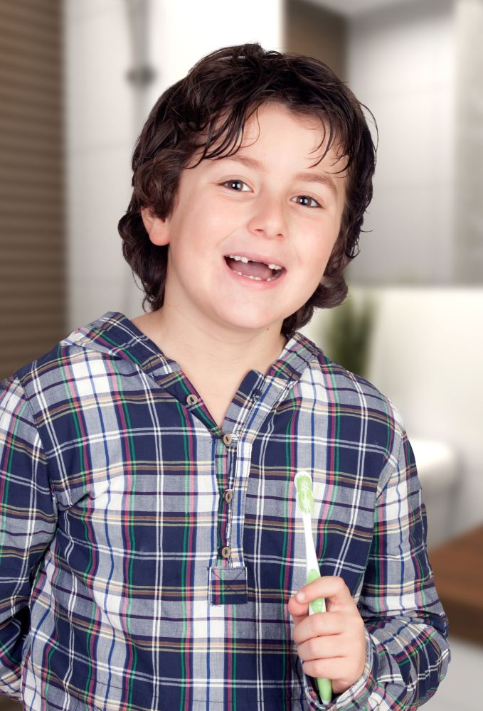Funny child without some teeth brushing his teeth in the bathroom