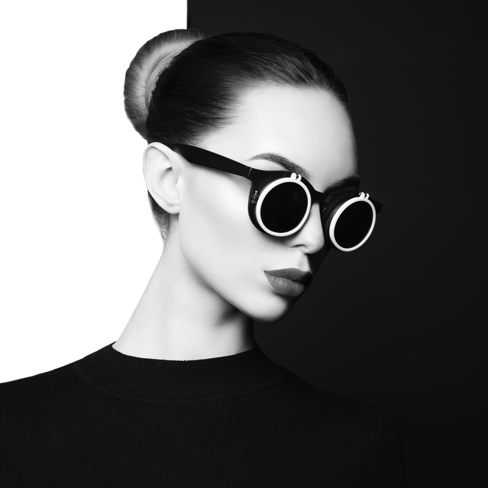 young sexy lady with black stylish sunglasses in black-and-white studio. beautiful woman with perfect lips and black lipstick pose in photostudio. Fashion portrait of fashionable model.