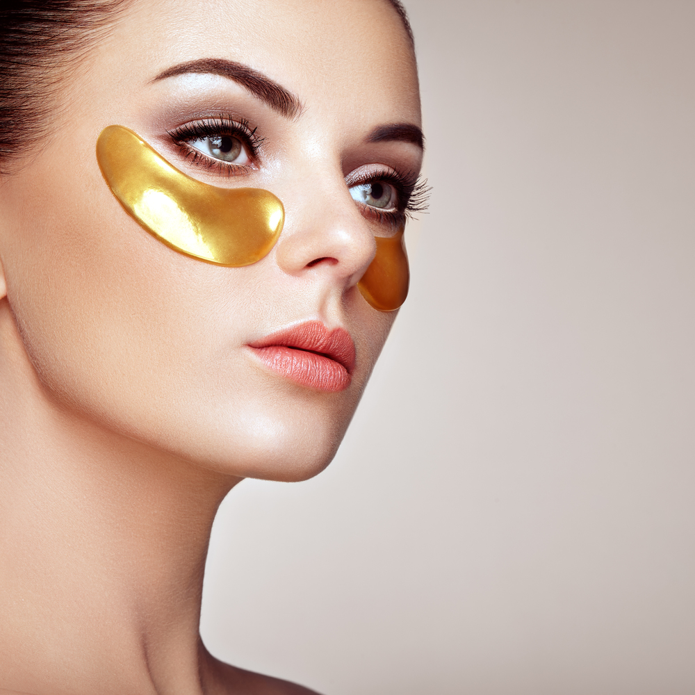 Portrait of Beauty Woman with Eye Patches. Woman Beauty Face with Mask under Eyes. Beautiful Female with natural Makeup and Gold Cosmetics Collagen Patches on Fresh Facial Skin
