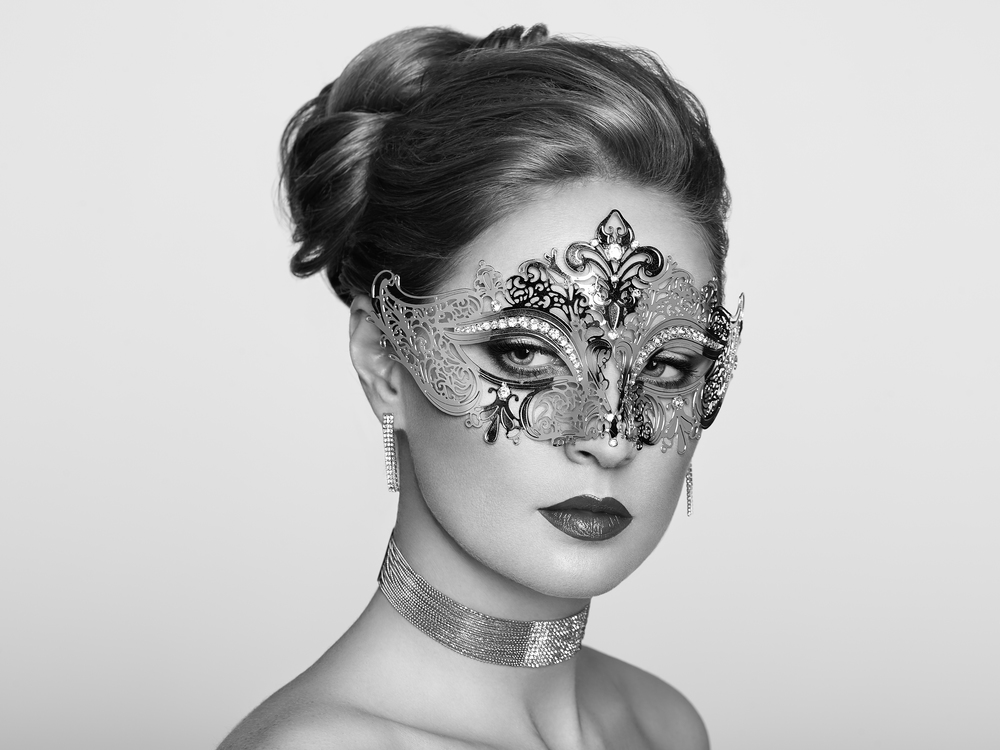Beautiful Woman Wearing Venetian Masquerade Carnival Mask at Party, over White Background. Christmas and New Year Celebration. Black and White Photo