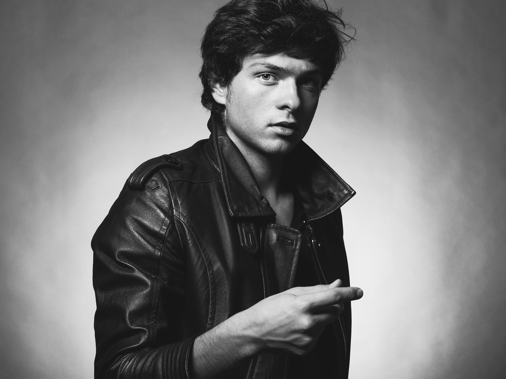 Portrait of Handsome Young Man. A Men in a Leather Jacket posing on a Gray Background. Black And White Photo