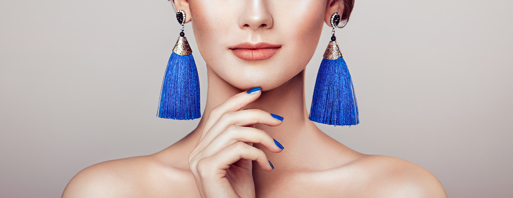 Beautiful woman with large earrings tassels jewelry blue color. Perfect makeup and nails manicure