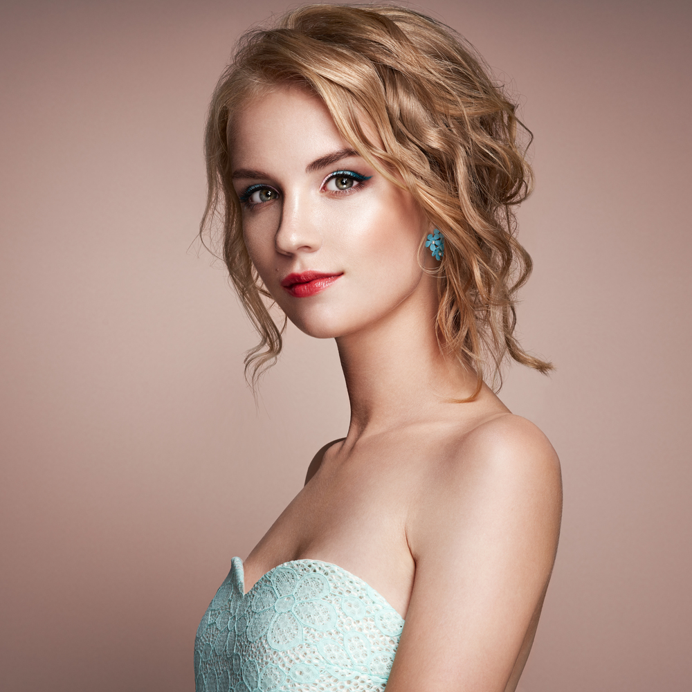 Blonde girl with elegant curly and shiny hairstyle. Beautiful model woman with curly hairstyle. Care and beauty hair products. Perfect make-up