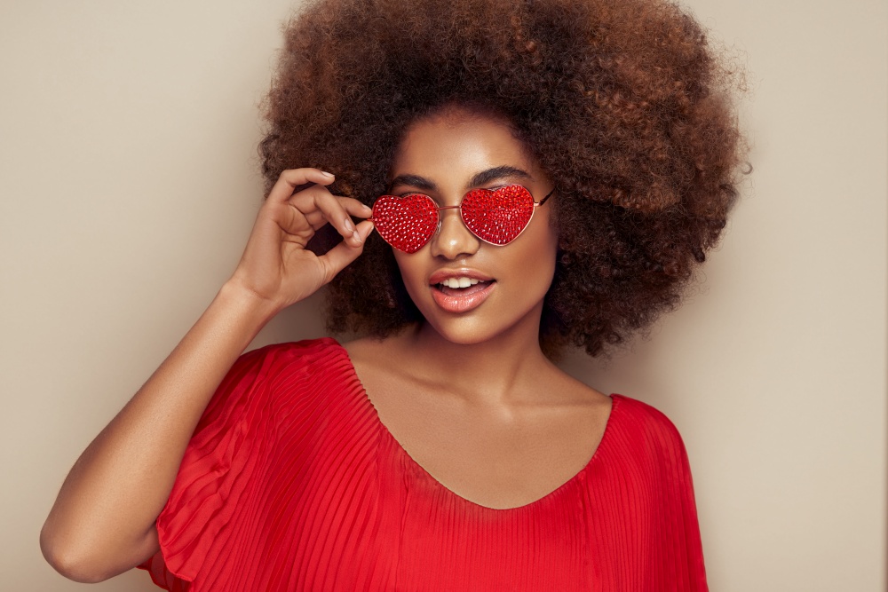 Beautiful portrait of an African girl in sunglasses in the shape of hearts. Valentine&rsquo;s Day. Symbol of love