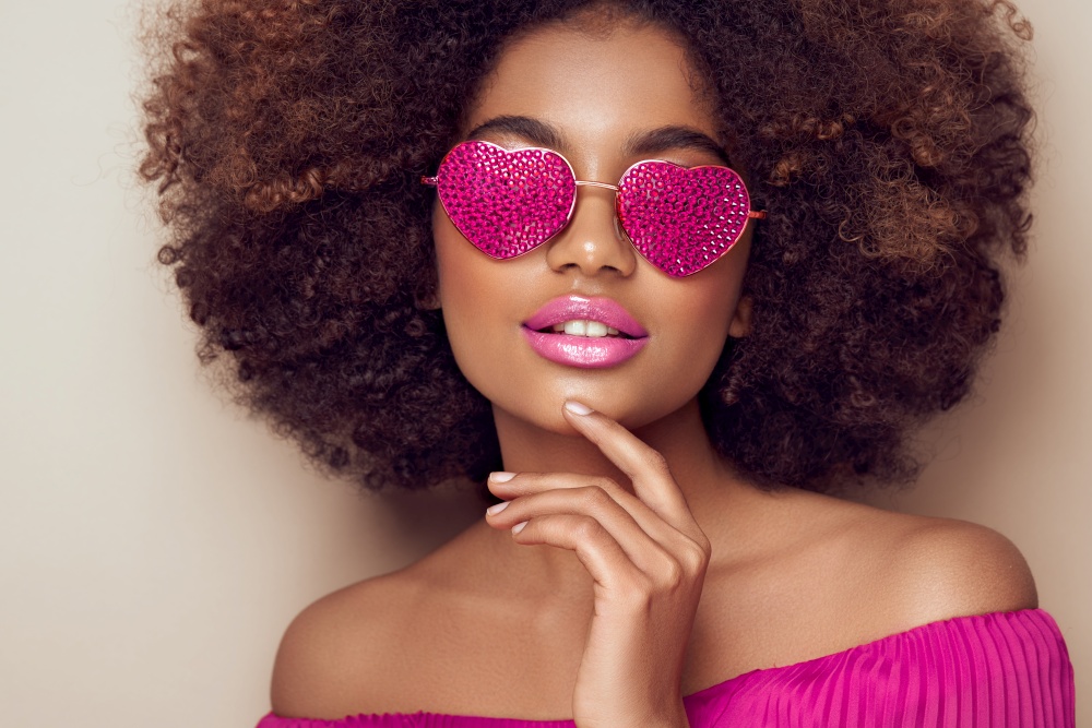 Beautiful portrait of an African girl in sunglasses in the shape of hearts. Valentine&rsquo;s Day. Symbol of love