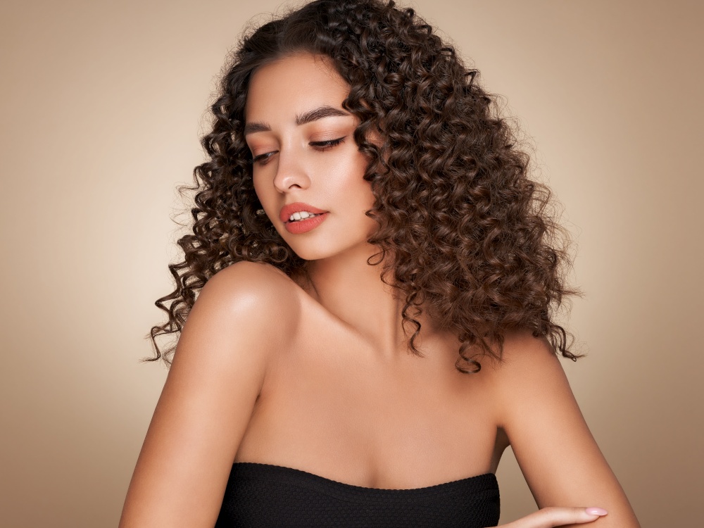 Fashion studio portrait of beautiful smiling woman with afro curls hairstyle. Fashion and beauty