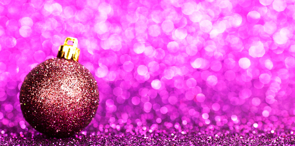 Beautiful purple christmas ball on abstract glitter background close-up