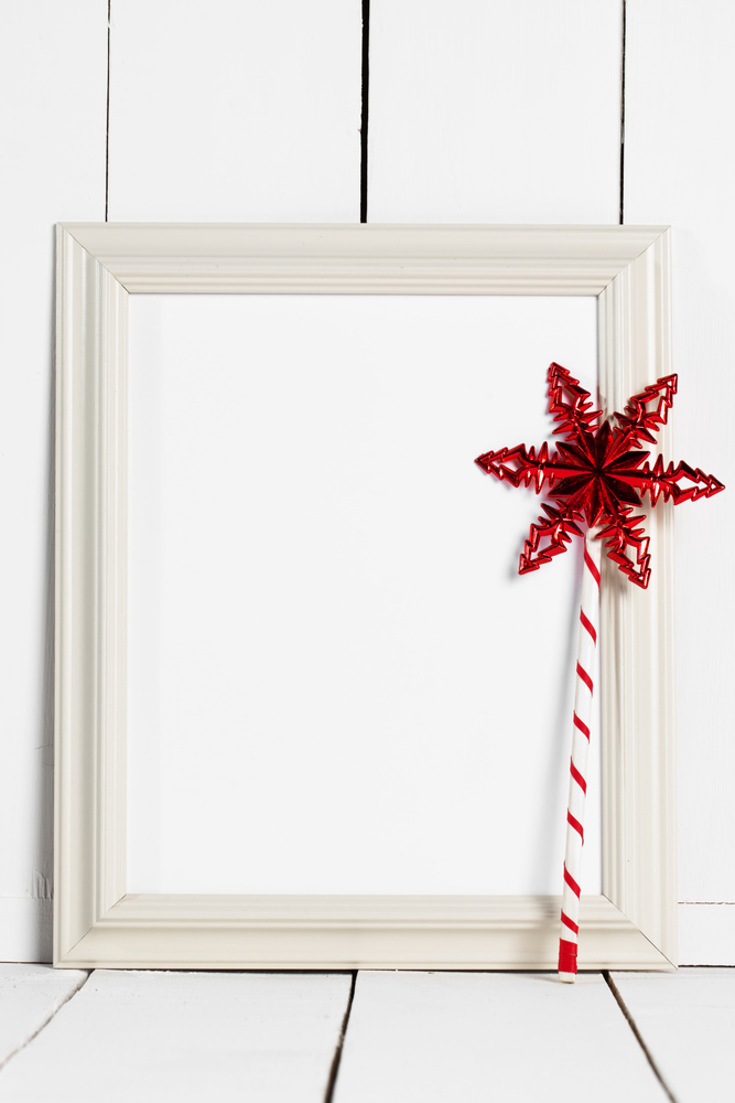 Vintage white wooden picture frame with blank white copy space and red star magic wand. Picture frame and magic wand