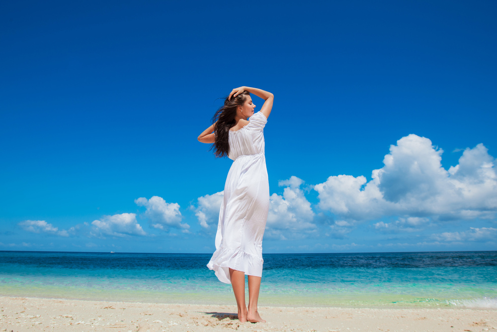 Woman relaxing at the beach enjoying her freedom wear long white dress. Woman relaxing at the beach