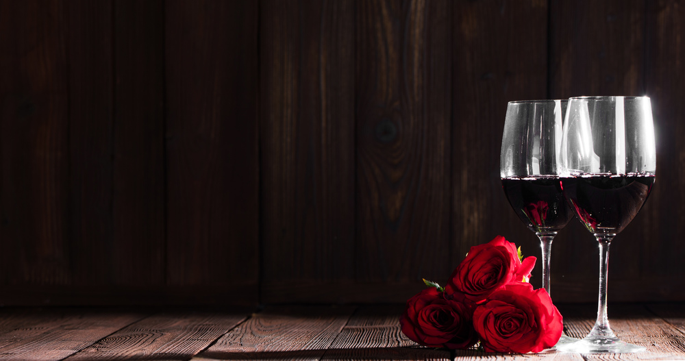 Two glasses of red wine and three roses, Valentine day. Wine and roses