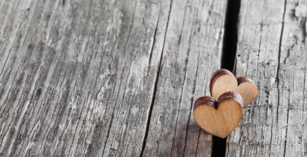 Two small wooden hearts on old cracked wood background. Two wooden hearts