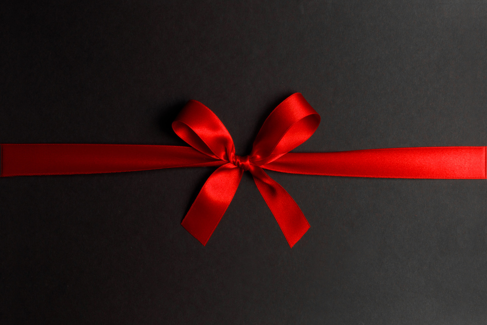 Shiny red satin ribbon and bow on black background. Holiday gift concept. Shiny red satin ribbon bow