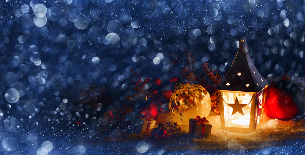 Christmas holidays card with gifts , balls , santa claus hat and glowing lantern in snow in the evening. Christmas decor in snow