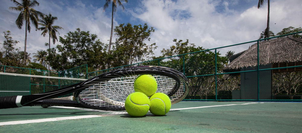 Tennis balls and racket in outdoor tropical court. Tennis balls and racket in the court