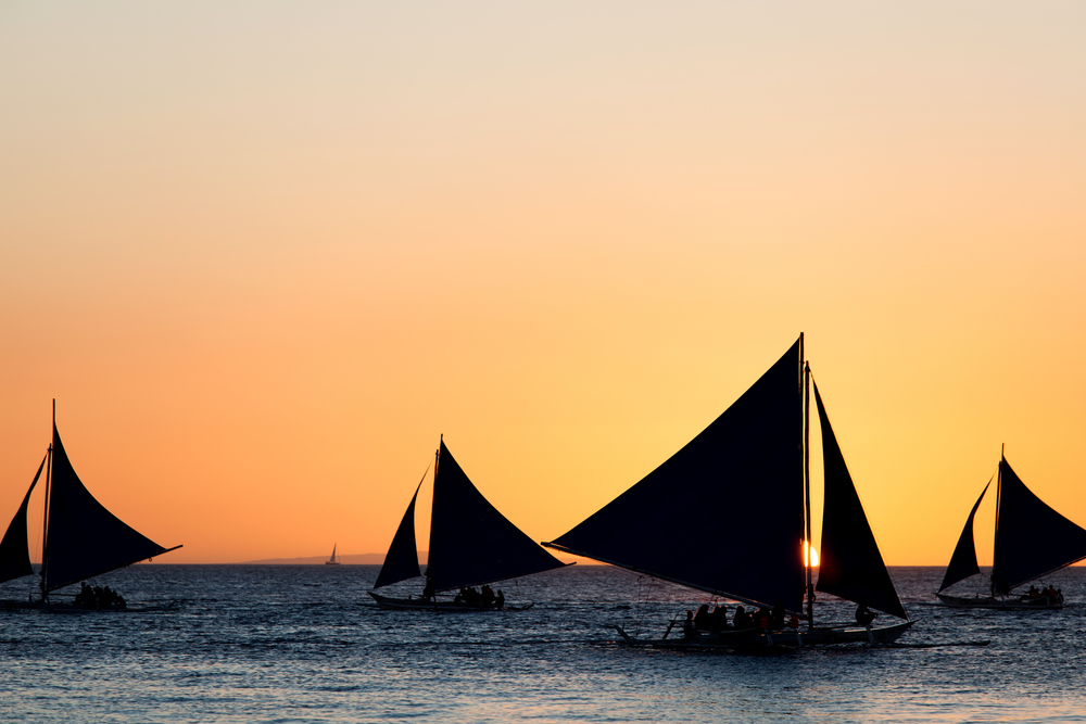 Sailing boats silhouette at orange sunset background. Sailing boats at sunset