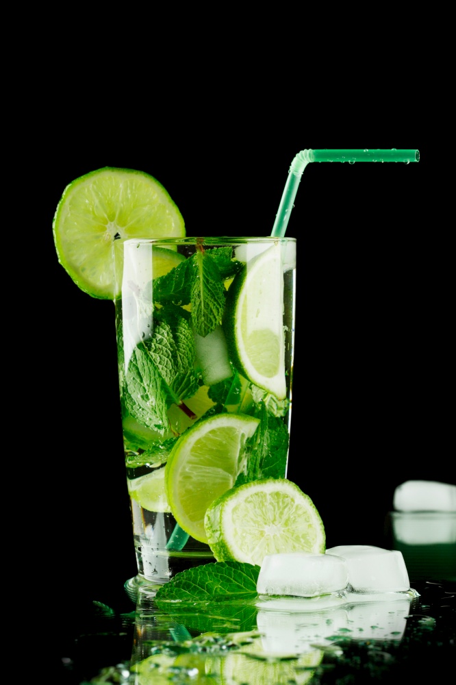 Mojito cocktail with lime, mint and ice on black background. Mojito cocktail on black