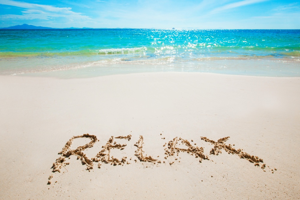 Realax word writing on tropical sea beach. Realax writing on a beach