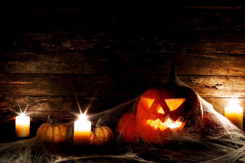 Halloween, decorations and holidays concept - pumpkins with spiders, web and candles. Halloween decorations concept