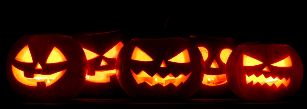 Many Halloween Pumpkin glowing faces in a row isolated on black background. Many Halloween Pumpkins on black